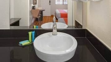Een badkamer met een witte wastafel, een spiegel en toiletartikelen op het aanrecht.