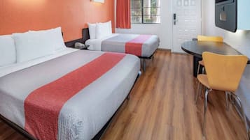 A hotel room with two beds, a desk, a chair, and a television.