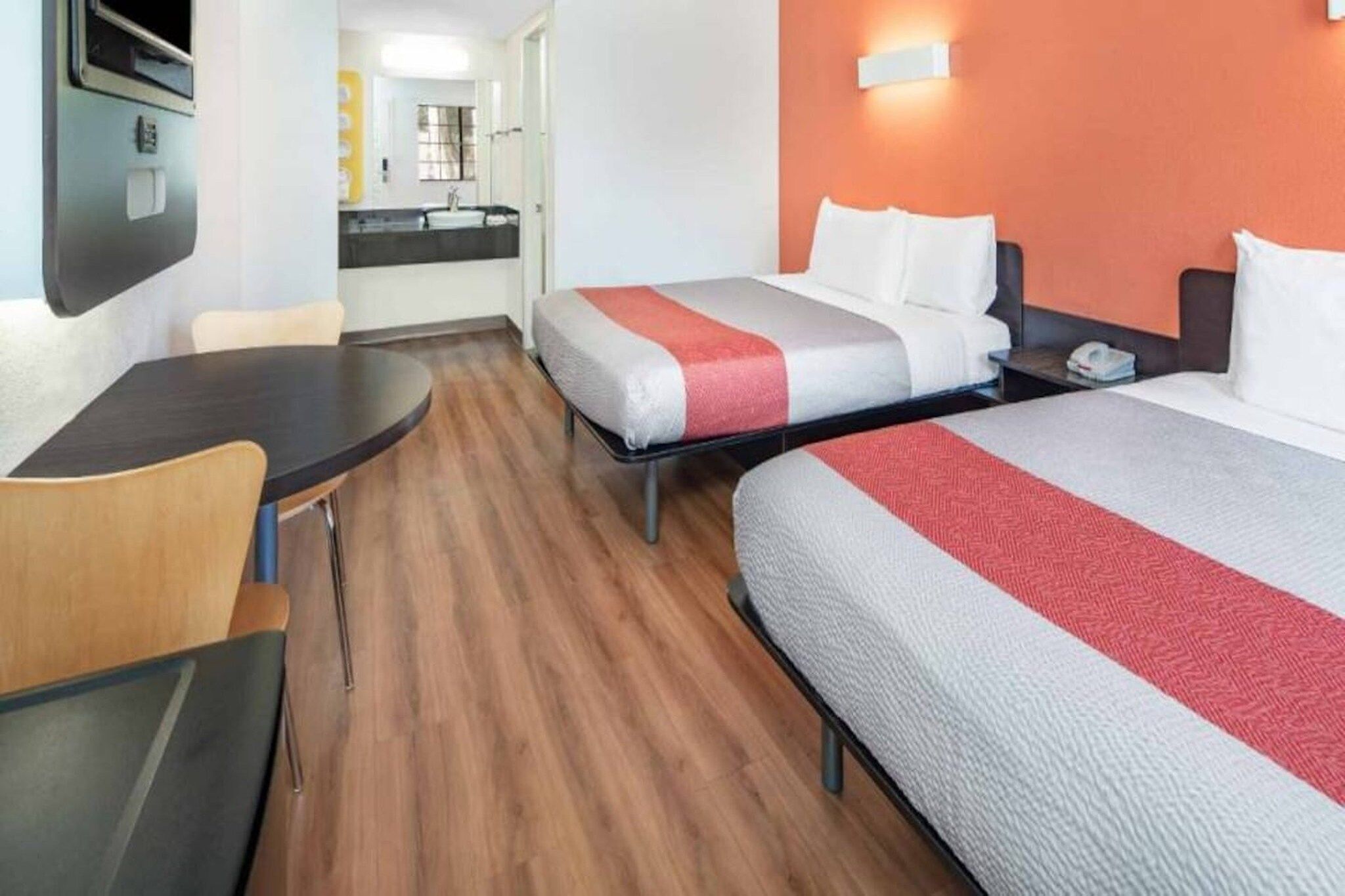 Een hotelkamer met twee bedden, een bureau en een badkamer op de achtergrond.