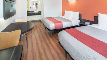 Een hotelkamer met twee bedden, een bureau en een badkamer op de achtergrond.