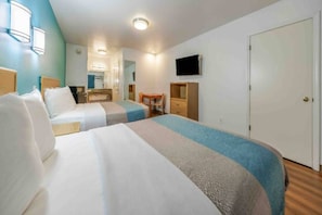 A hotel room with two beds, a desk, a chair, a television, and a wardrobe.