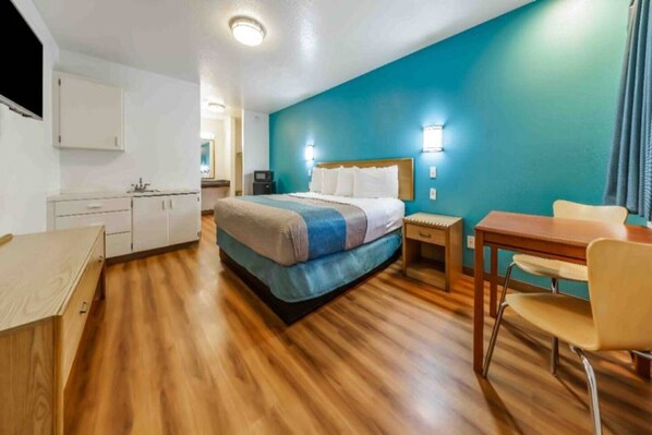 Une chambre d’hôtel comprenant un lit, un bureau, une chaise, une petite table et un placard.