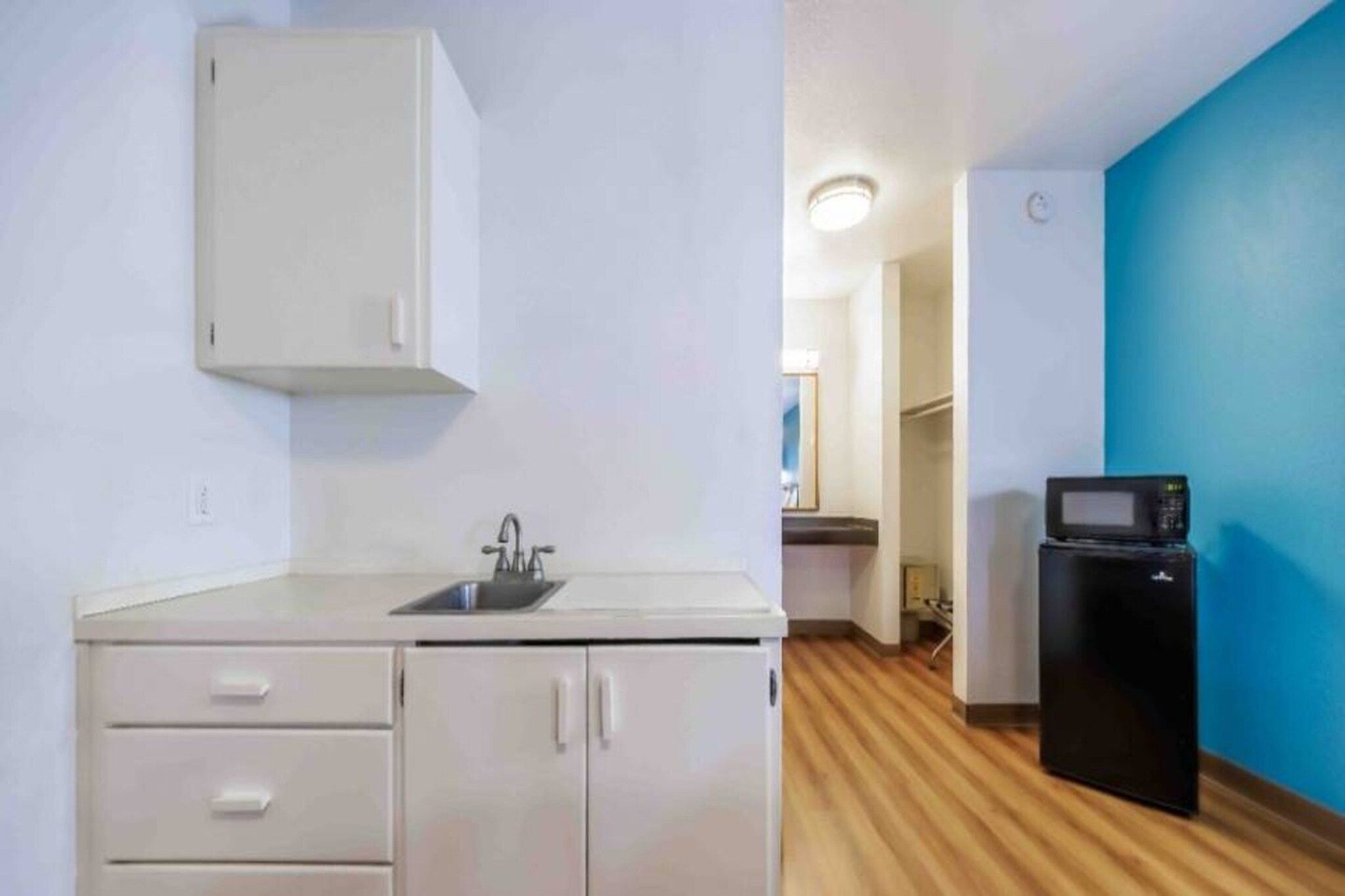 A small kitchenette with a sink, cabinets, and a microwave.