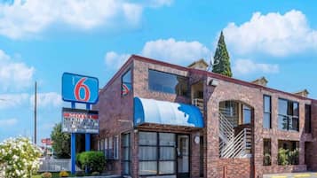 A motel with a prominent '6' sign, a lobby entrance, and a parking lot.