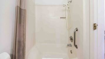 Une salle de bain avec une douche, des toilettes et une porte.