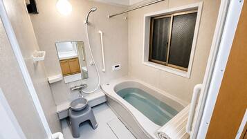 A compact bathroom with a bathtub, toilet, and a window.