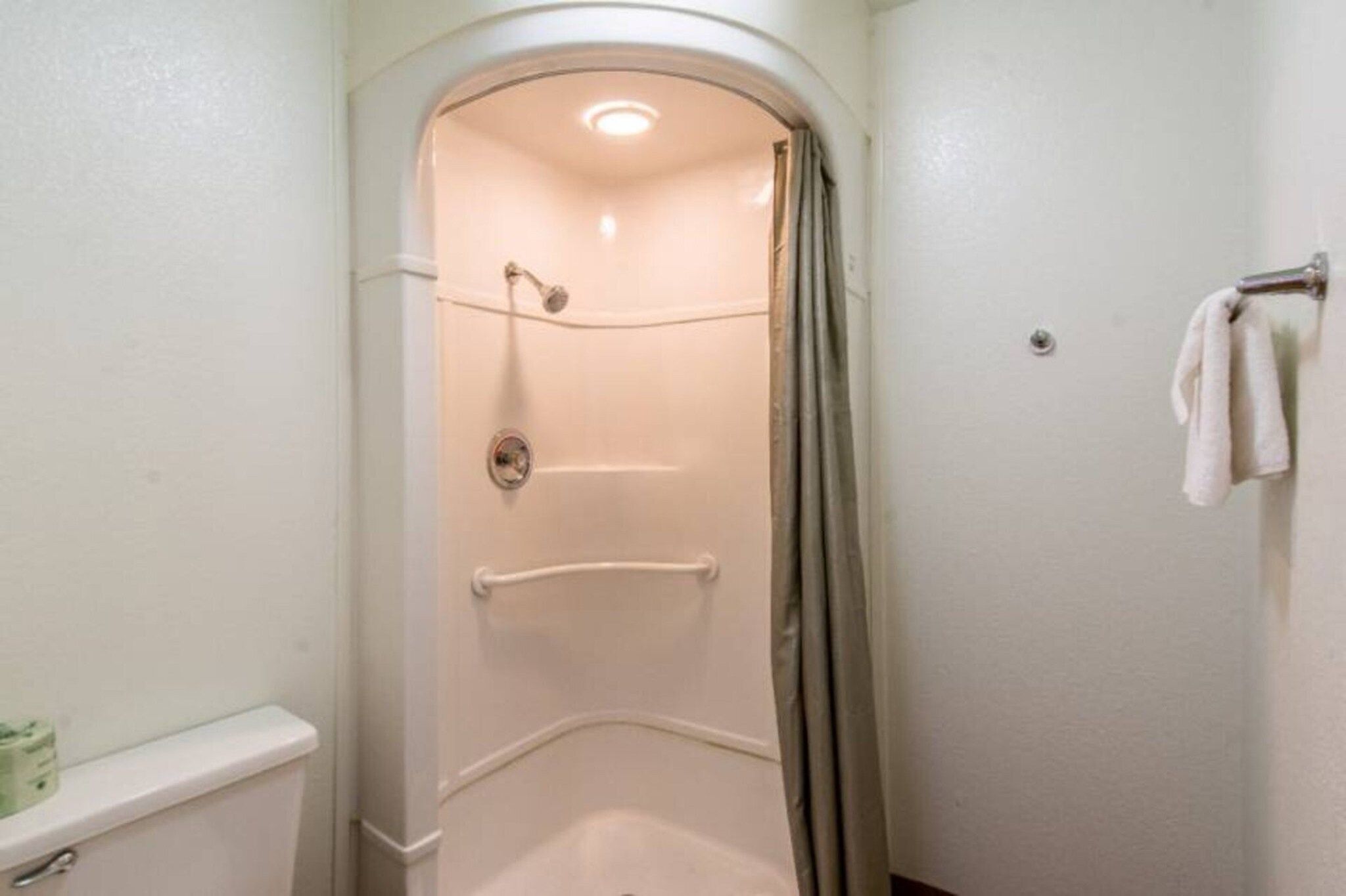 Un petit espace douche fermé, doté d’une porte, d’un porte-serviettes et de toilettes.