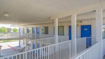 A motel with a covered outdoor area, multiple rooms with blue doors, and a white railing.