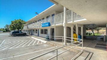 A motel with a 'WELCOME' sign, a covered parking area, and a building with multiple windows.