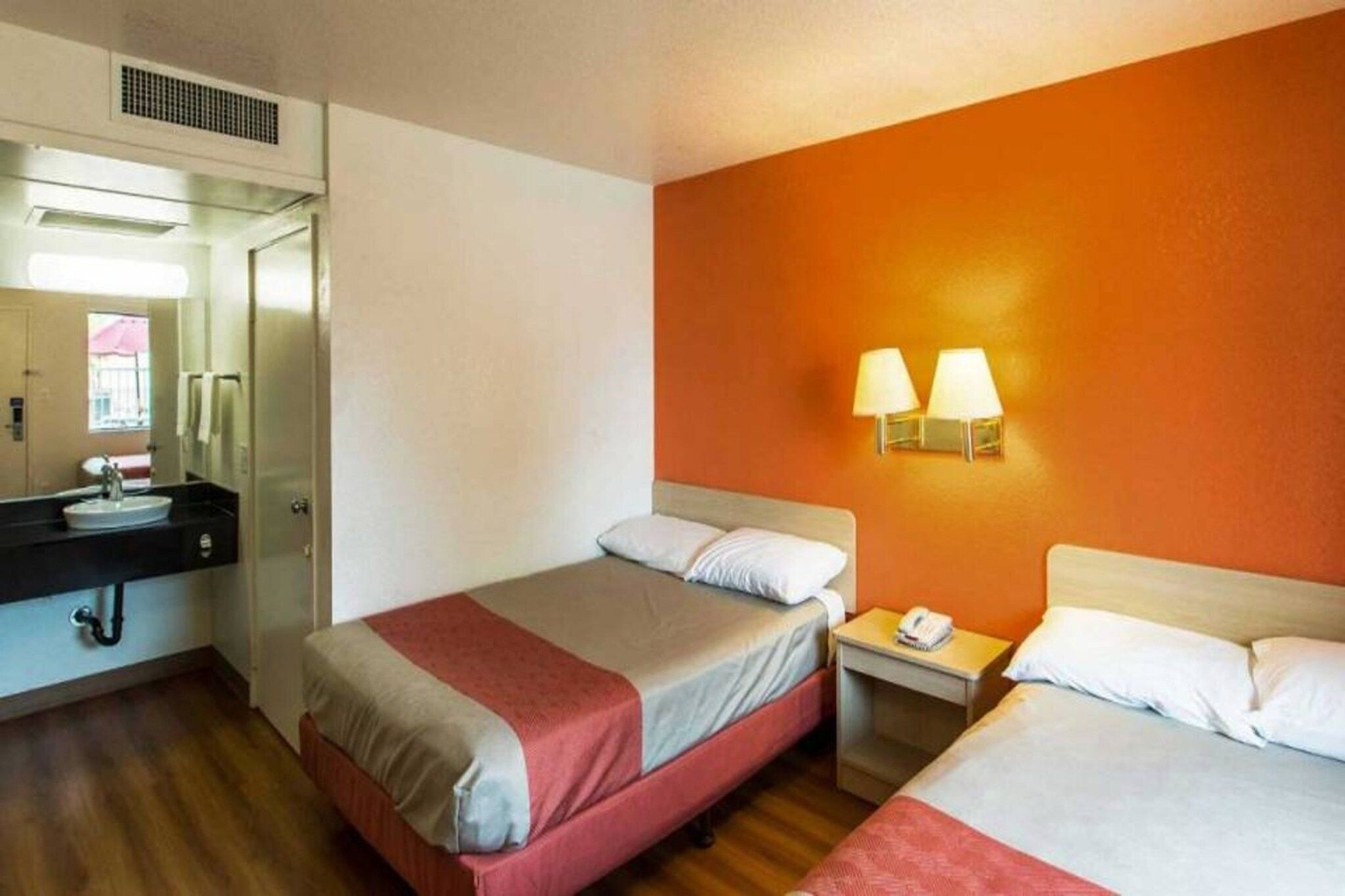 A hotel room with two beds, a bathroom, and a nightstand with a phone.