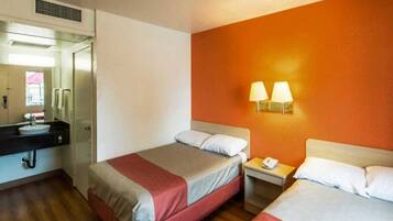 A hotel room with two beds, a bathroom, and a nightstand with a phone.