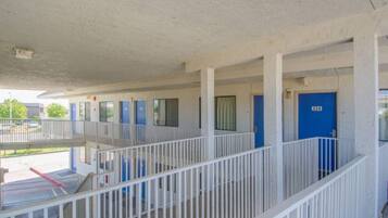 A motel with a covered outdoor area, multiple rooms with blue doors, and a white railing.