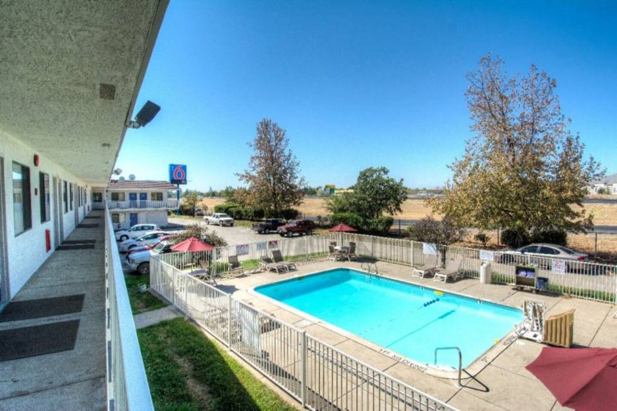 A hotel with a swimming pool, outdoor seating, and a clear view of the surrounding landscape.