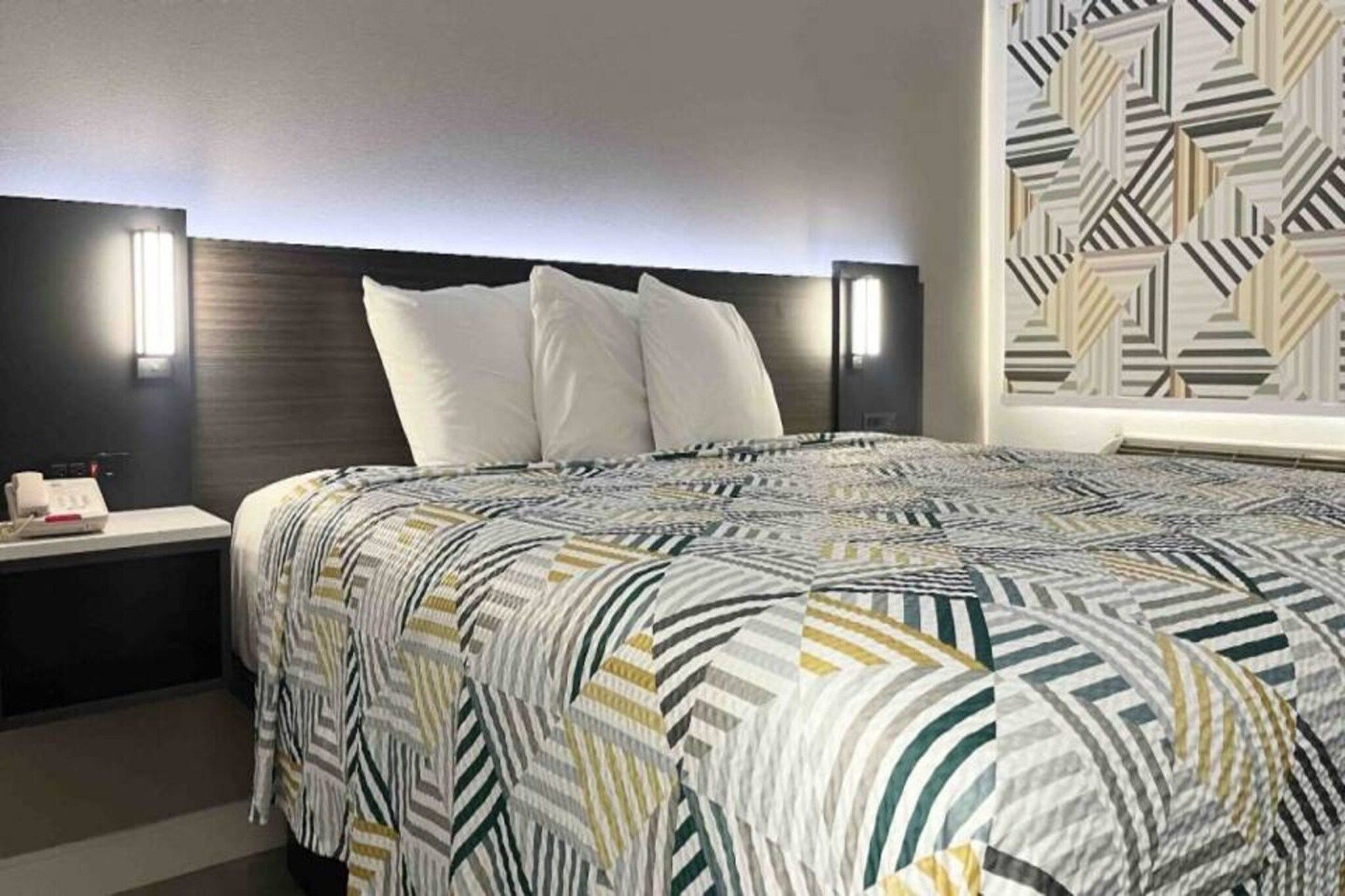 Ein Hotelzimmer mit Bett, Nachttischen und einer Wand mit Muster.