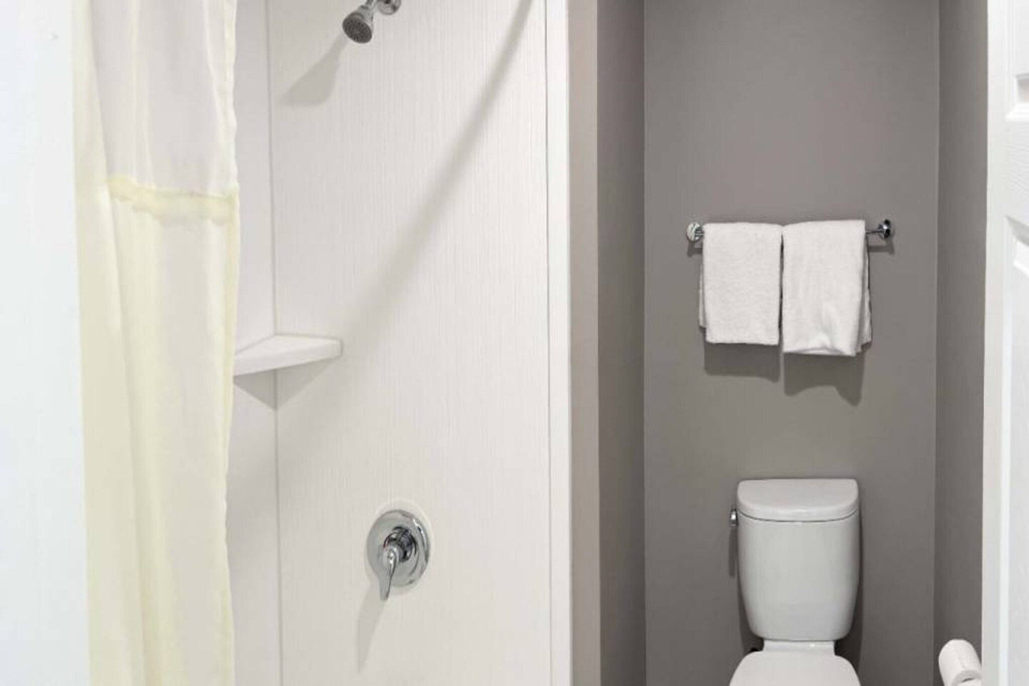 A bathroom with a shower, a toilet, and a towel rack.