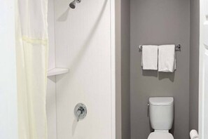 A bathroom with a shower, a toilet, and a towel rack. - King Bed | ADA/RI Shower/Micfridge (Morro Bay)