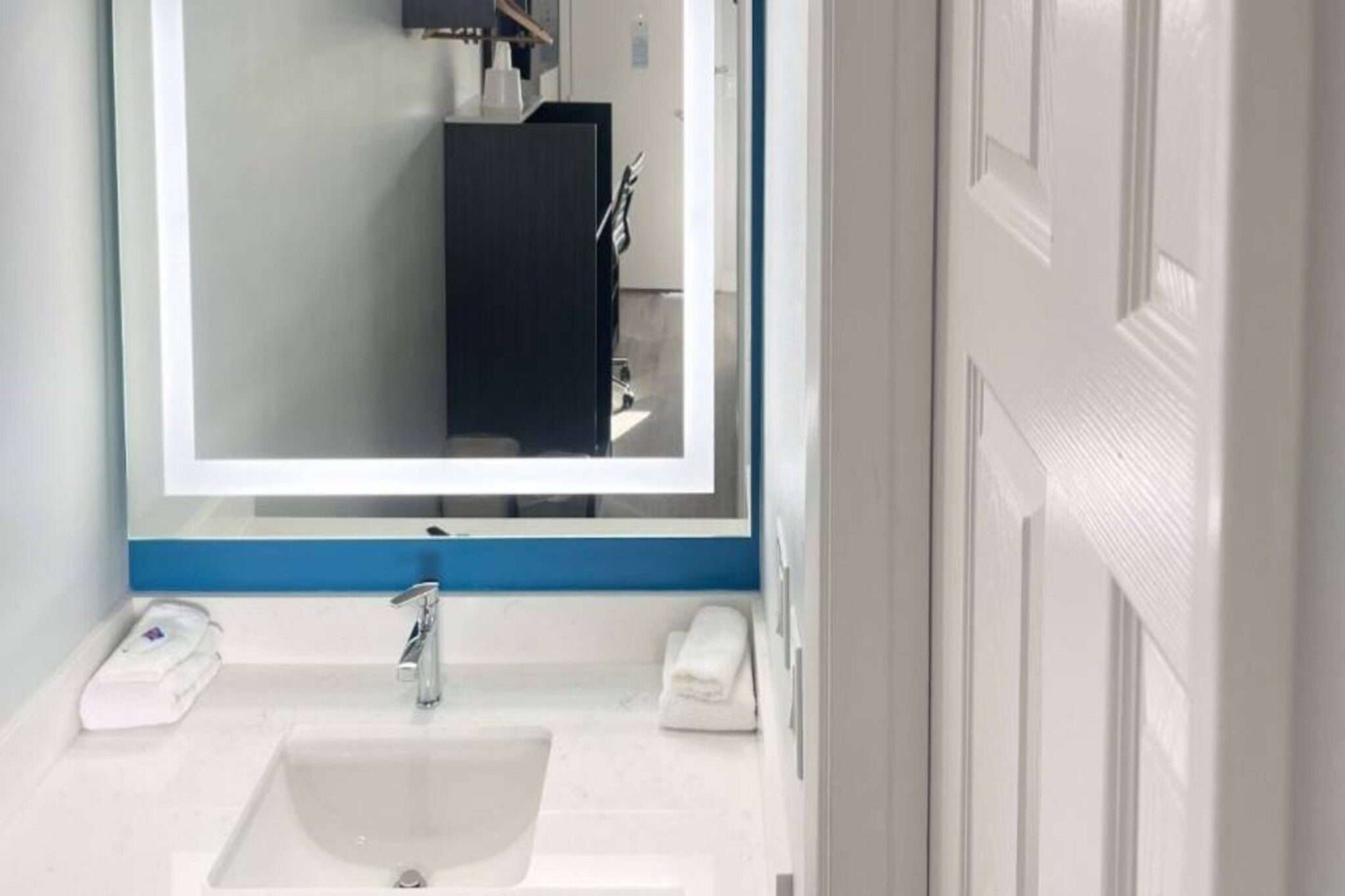 A bathroom with a white sink, a mirror, and a towel rack.