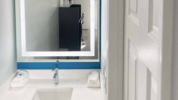 A bathroom with a white sink, a mirror, and a towel rack.
