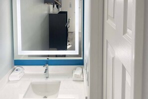 A bathroom with a white sink, a mirror, and a towel rack. - Spacious King Bed|Micfridge|Pool (Morro Bay)