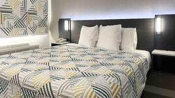 Quarto de hotel com uma cama grande, mesa de cabeceira e parede com padrão.