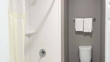 A bathroom with a shower, a toilet, and a towel rack.