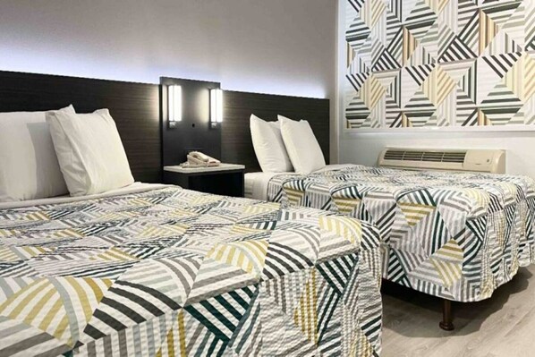 Een hotelkamer met twee bedden, een nachtkastje met een telefoon en een kamer met een patroon op de muur.