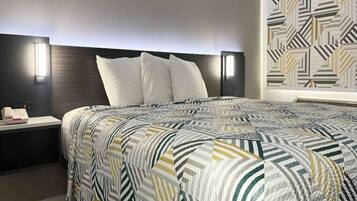 A hotel room with a bed, nightstands, and a patterned wall.