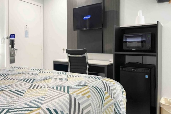 A hotel room with a bed, a desk, a chair, a television, and a microwave. - Spacious King Bed, Pool|Free Wifi (Morro Bay)
