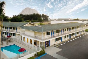 A motel with a swimming pool, multiple balconies, and a mountain in the background. - Spacious King Bed, Pool|Free Wifi (Morro Bay)
