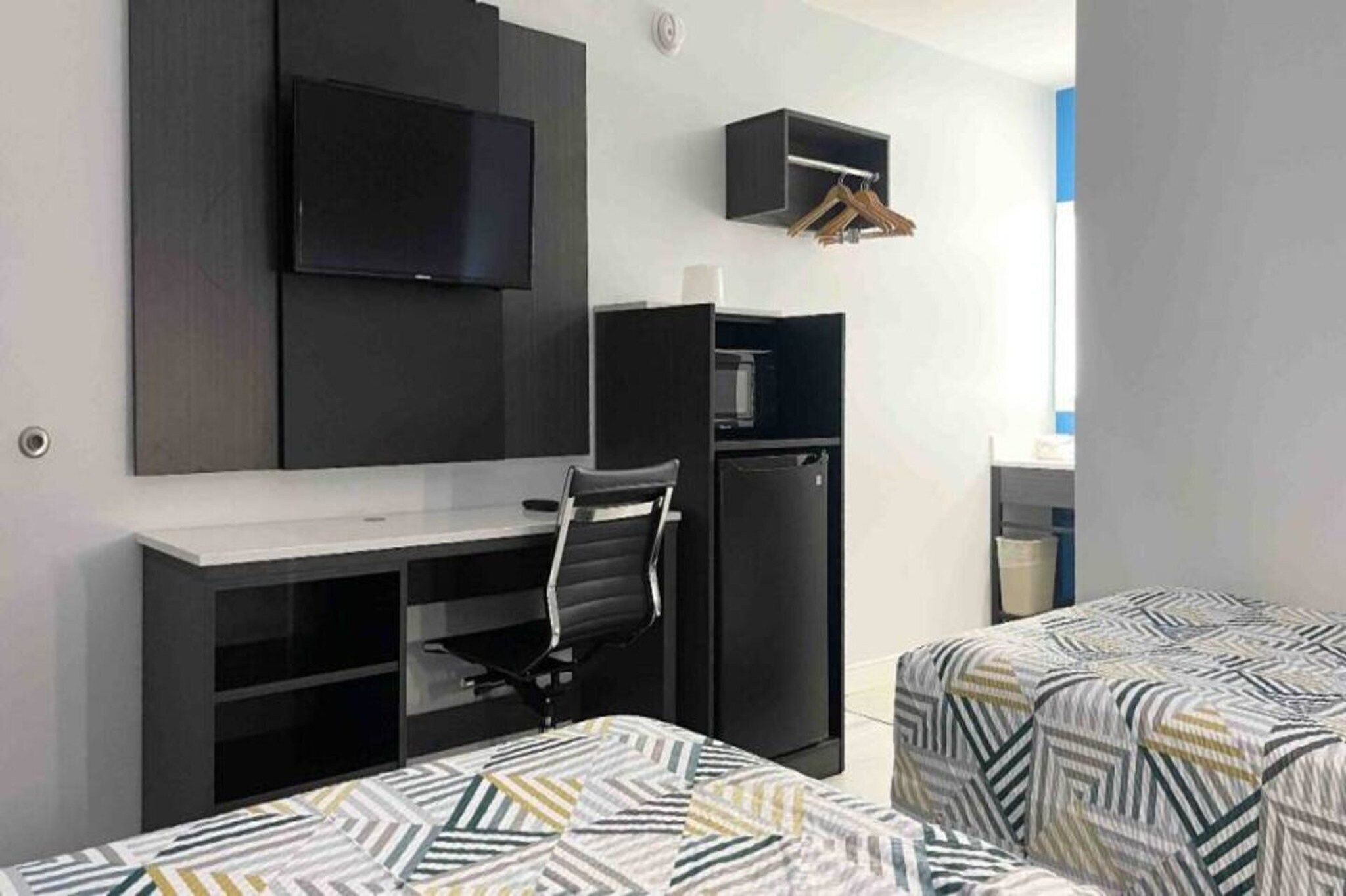 A room with a bed, a desk, a chair, a television, and a wardrobe.