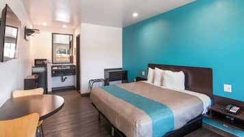 A hotel room with a bed, a desk, a chair, a mirror, and a window.