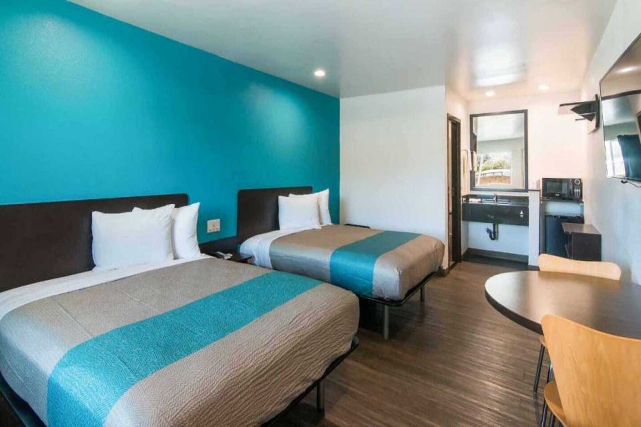 Quarto de hotel com duas camas, uma kitchenette, área de refeições e banheiro.