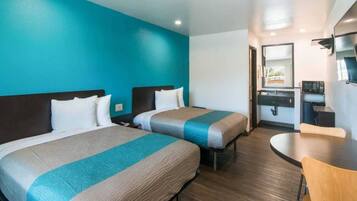 Quarto de hotel com duas camas, uma kitchenette, área de refeições e banheiro.