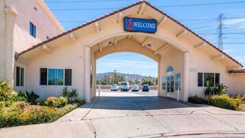 A building entrance with a 'Welcome' sign, a lobby, and a parking lot with cars.