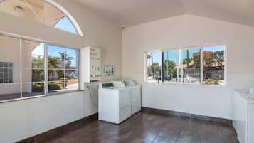 Uma lavanderia com máquina de lavar, secadora e uma janela grande com vista para o exterior.