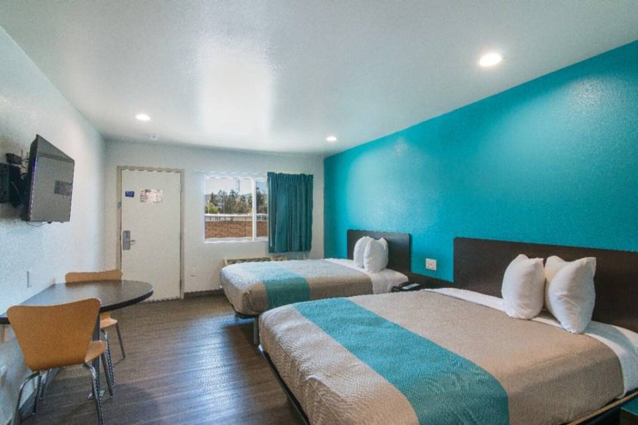 A hotel room with two beds, a desk, and a television.