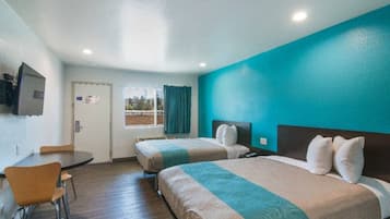 A hotel room with two beds, a desk, and a television.