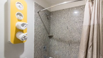 Un baño con ducha, inodoro y un perchero con tres toallas.