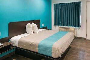 A hotel room with a bed, a nightstand, a window with curtains, and a wall heater. - 1 Queen Bed | Smoking, Micfridge (South El Monte)