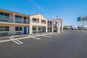 A motel with a two-story building, a covered parking area, and a billboard in the background. - 1 Queen Bed | Smoking, Micfridge (South El Monte)