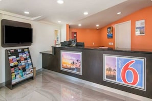 A hotel reception area with a digital display, a magazine rack, and a wall-mounted sign. - 1 Queen Bed | Smoking, Micfridge (South El Monte)