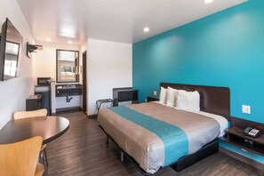 Una habitación de hotel con cama, escritorio, silla, espejo y ventana.