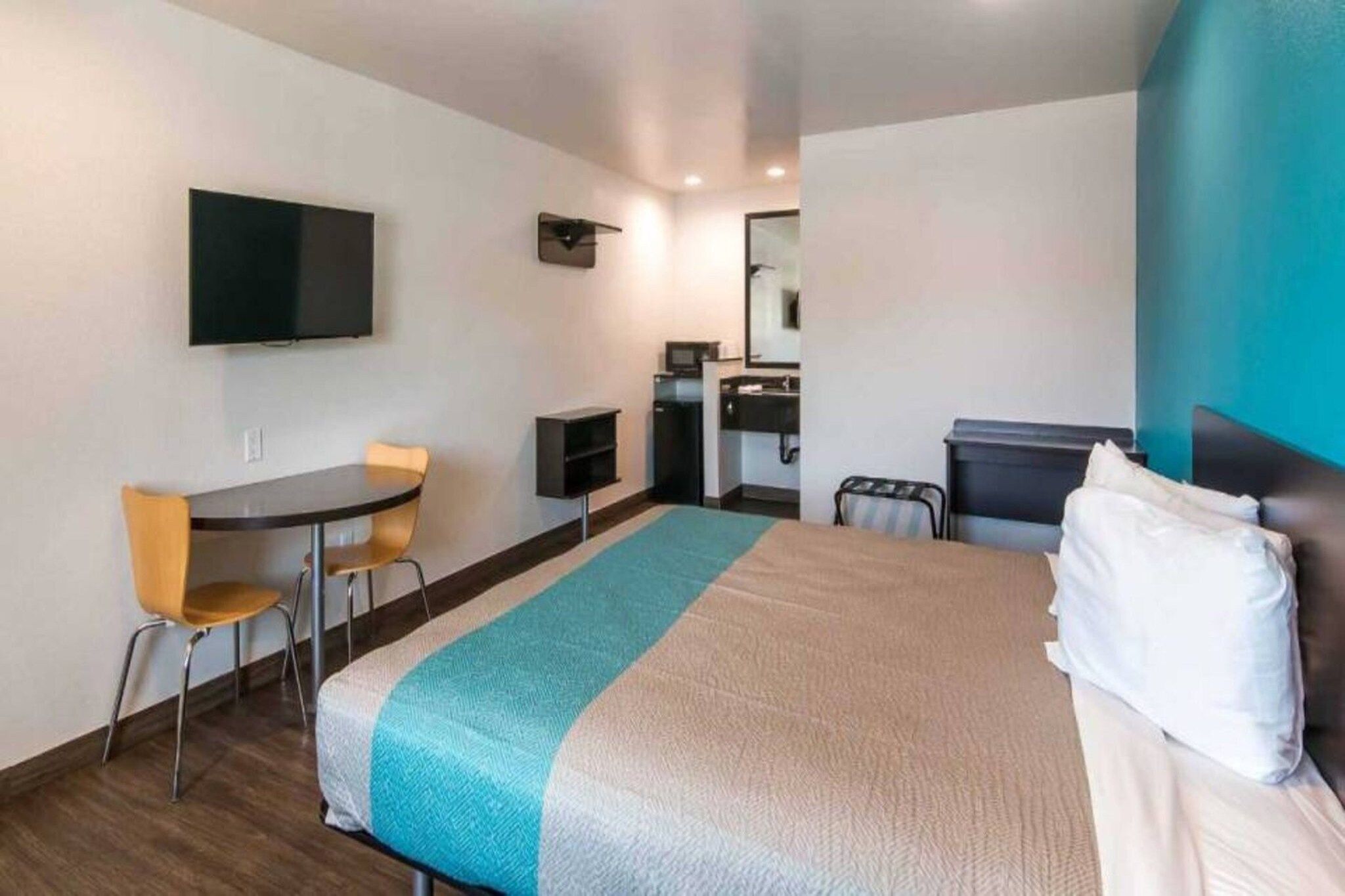A hotel room with a bed, a desk, a chair, a television, and a bathroom.