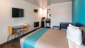 A hotel room with a bed, a desk, a chair, a television, and a bathroom.