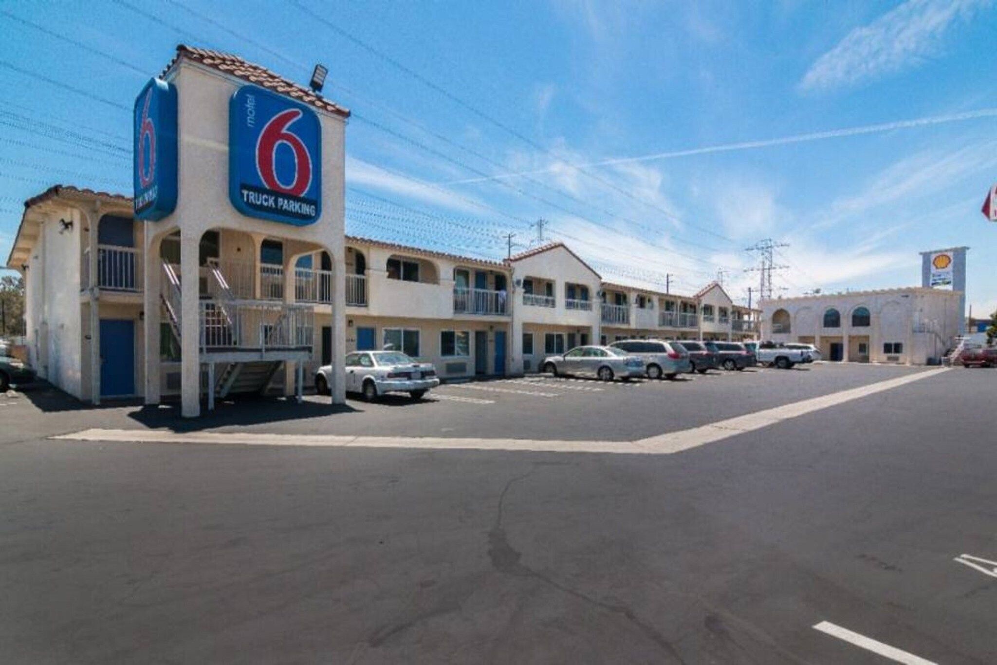 A motel with a '6' sign, multiple parking spaces, and a Shell gas station in the background.