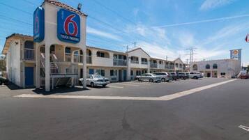 A motel with a '6' sign, multiple parking spaces, and a Shell gas station in the background.