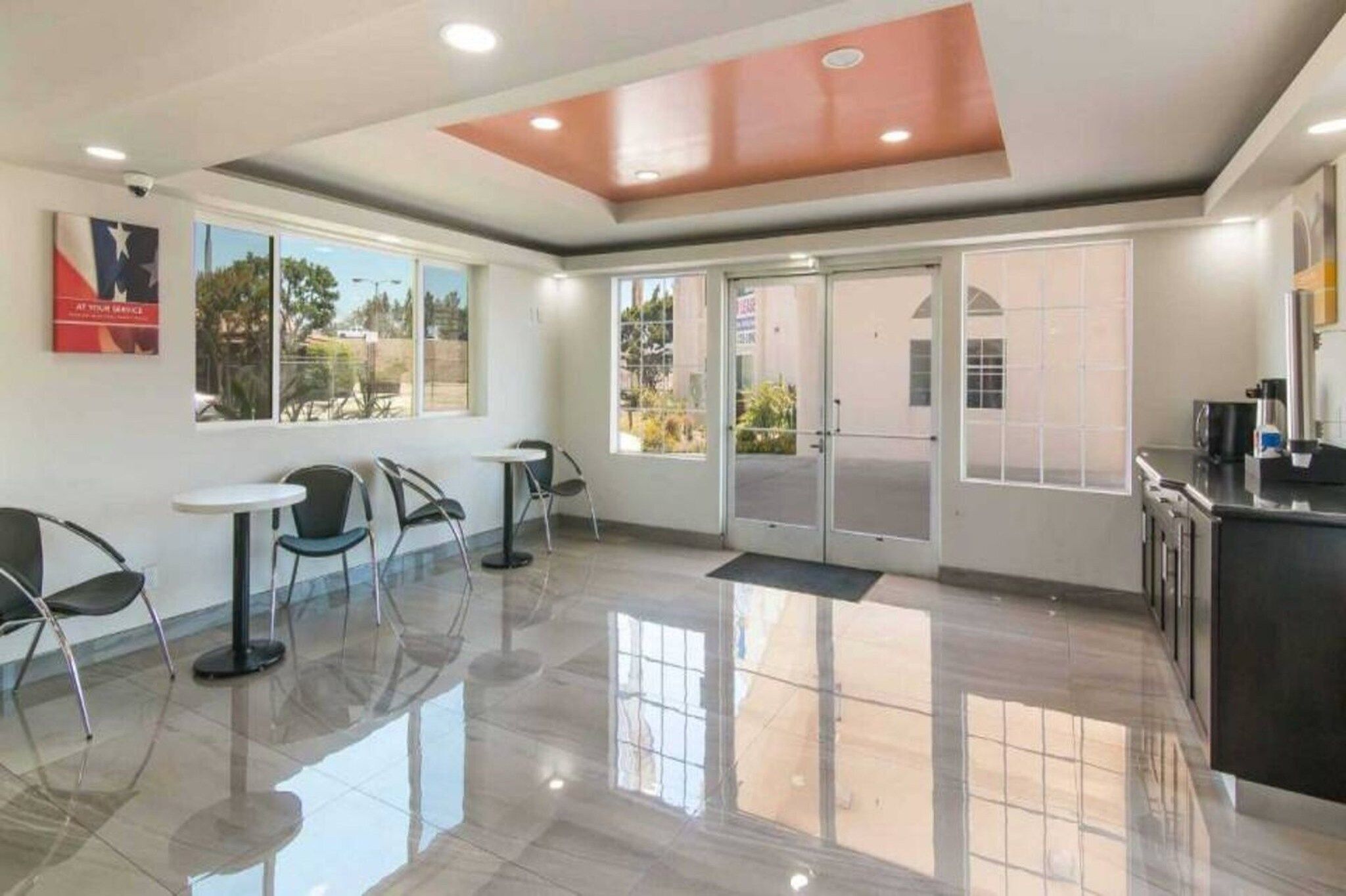A clean, modern lobby with a glass door entrance, a reception desk, and a seating area with chairs and tables.