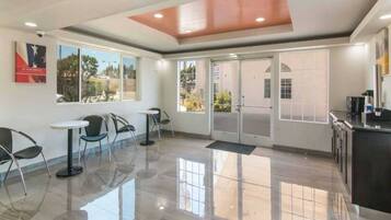 A clean, modern lobby with a glass door entrance, a reception desk, and a seating area with chairs and tables.