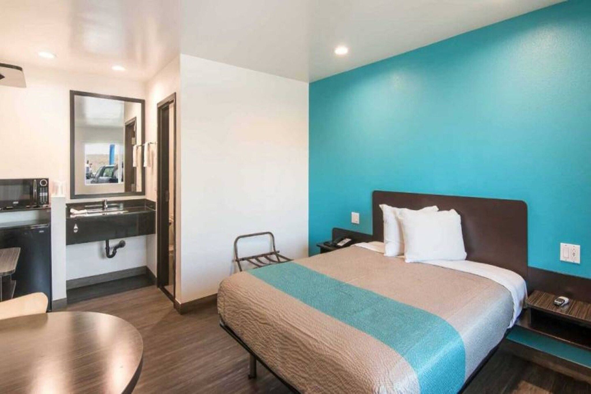 A hotel room with a bed, a desk, a chair, and a bathroom.
