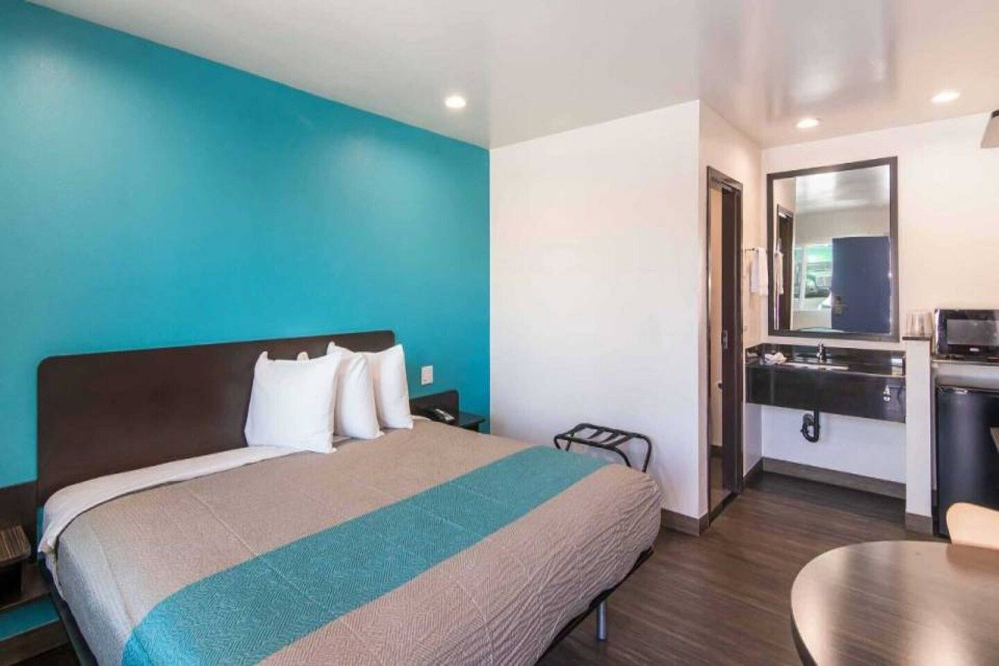 A hotel room with a bed, a desk, and a mirror.